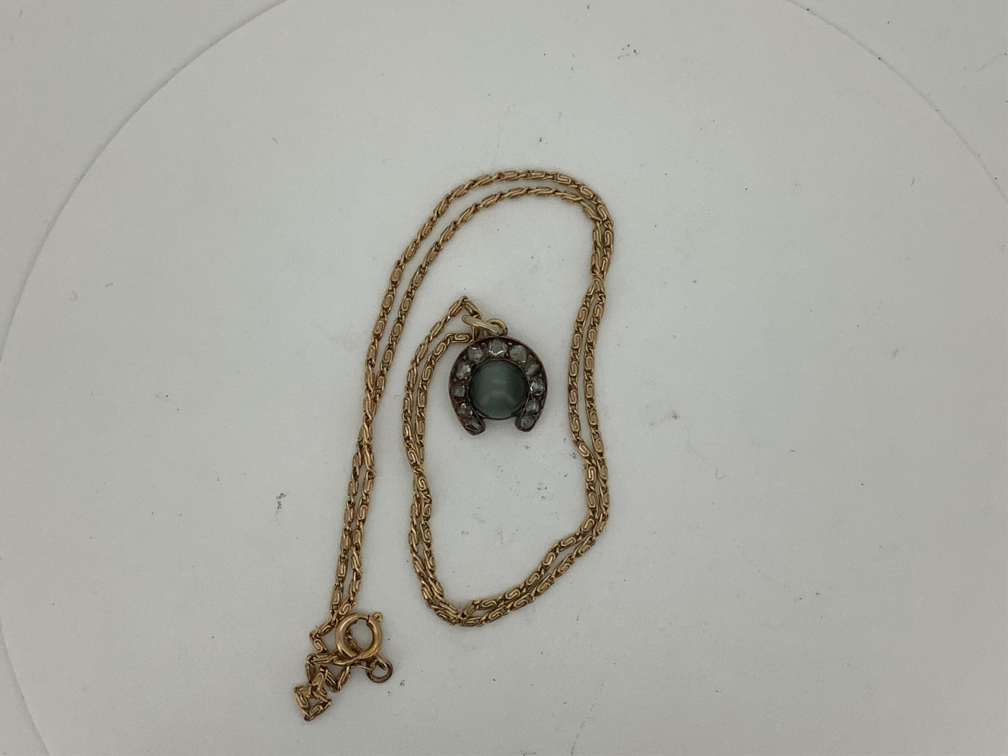 A yellow metal, cat's eye quartz and rose cut diamond cluster set horseshoe pendent, 11mm, together with a 9ct gold chain, 41cm, gross weight 5 grams.